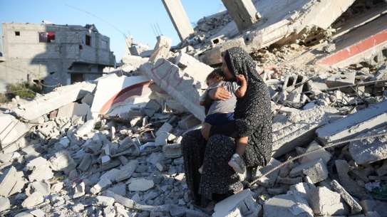 Woman hold her child in rubble in Gaza