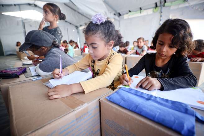 Children use cardboard boxes as desks