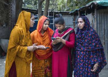 Kakoli and three friends look at their digital phones in Bangladesh