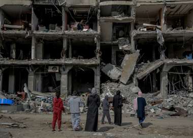 A family looks at an apartment block destroyed